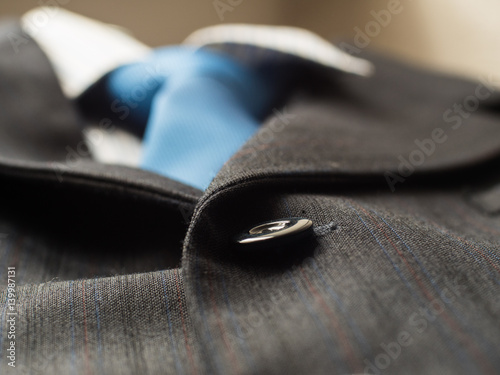 Black buttons on a man's suit background with blue tie, close up