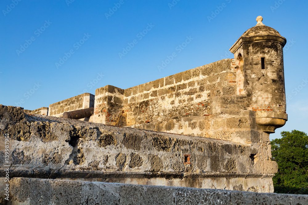 Sunset light hits a cannon and turret on the colonial era wall in Cartagena, Colombia.