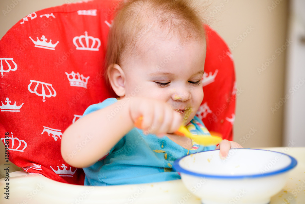 One year old child plays in the kitchen with dishes One year old child plays in the kitchen with dishes