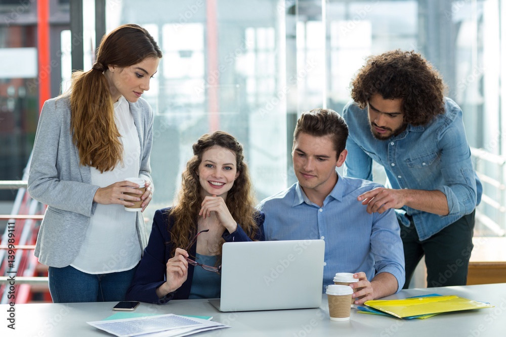 Smiling business team discussing over laptop in meeting Smiling business team discussing over laptop in meeting