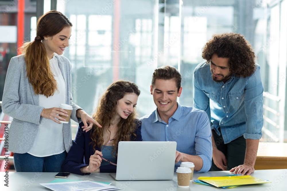 Smiling business team discussing over laptop in meeting Smiling business team discussing over laptop in meeting