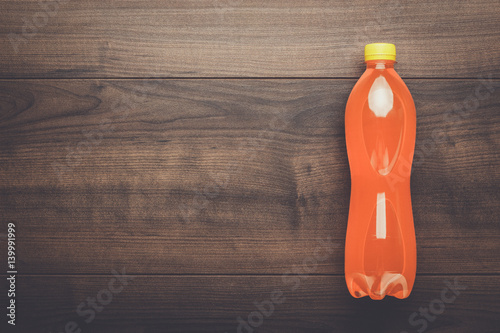 plastic bottle of orange soda on wooden table