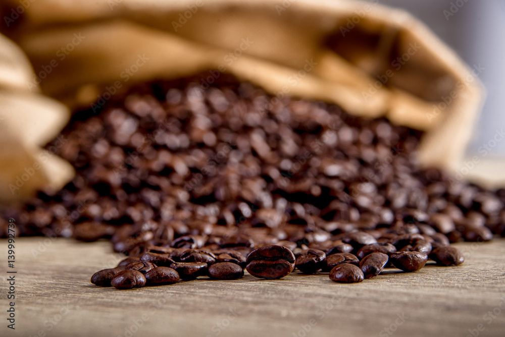 Fototapeta premium Spilled coffee beans on wooden