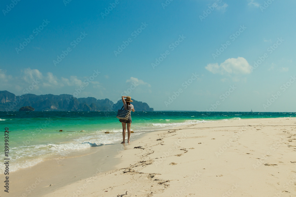 Girl with bag stands on a tropical beach. Poda island (Koh Poda), Krabi province, Thailand.