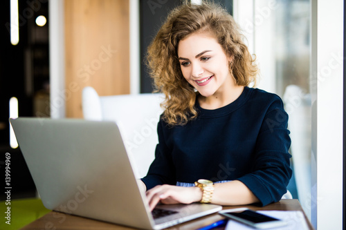 Φωτογραφία Happy curlu young woman use laptop in modern place with bright windows