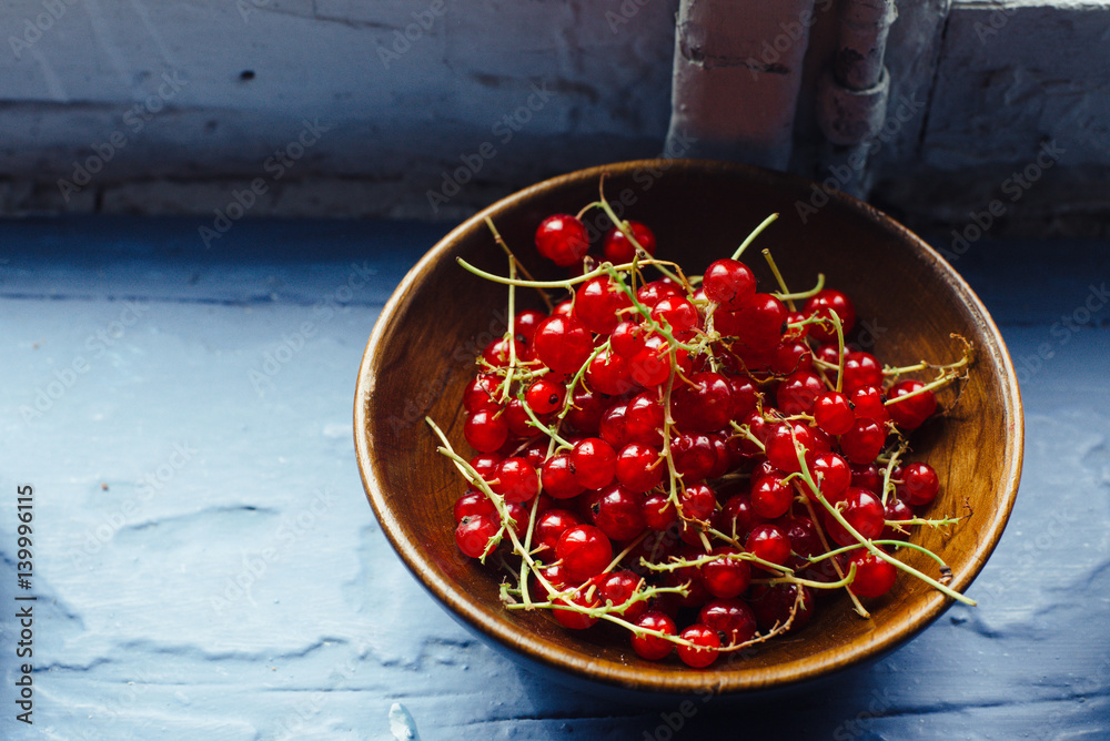 Red currant in a plate on a blue windowsill