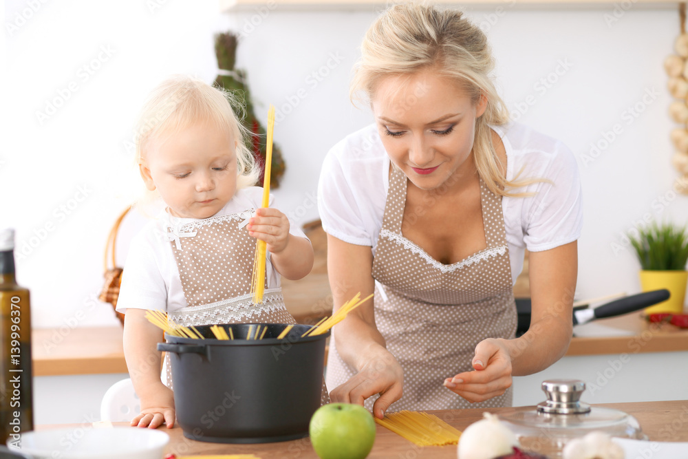 Happy family in the kitchen. Mother and child daughter cooking pasta Happy family in the kitchen. Mother and child daughter cooking pasta