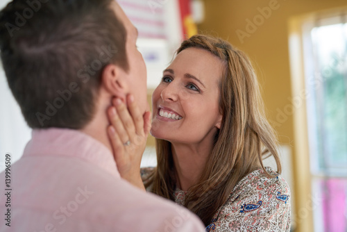 Tender loving moment between young beautiful couple woman smiling lovingly at husband 