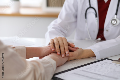 Hand of doctor  reassuring her female patient. Medical ethics and trust concept