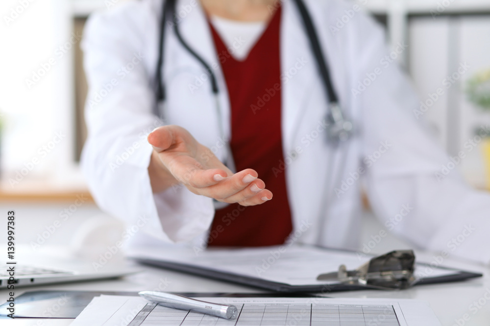 Fototapeta premium Close up of unknown female doctor typing on laptop computer while sitting at the table. Medical staff, compulsory work concept