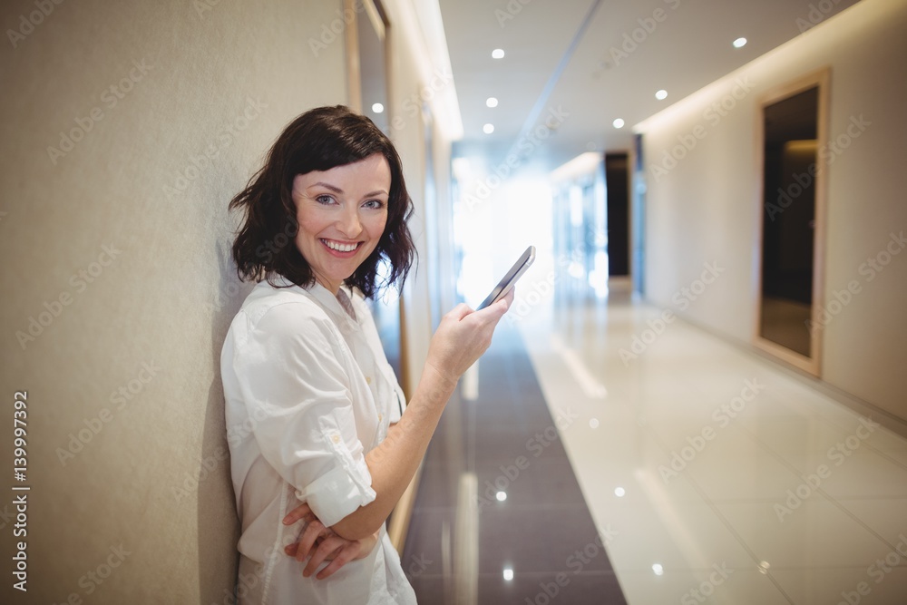 Portrait of female executive using mobile phone in corridor Portrait of female executive using mobile phone in corridor