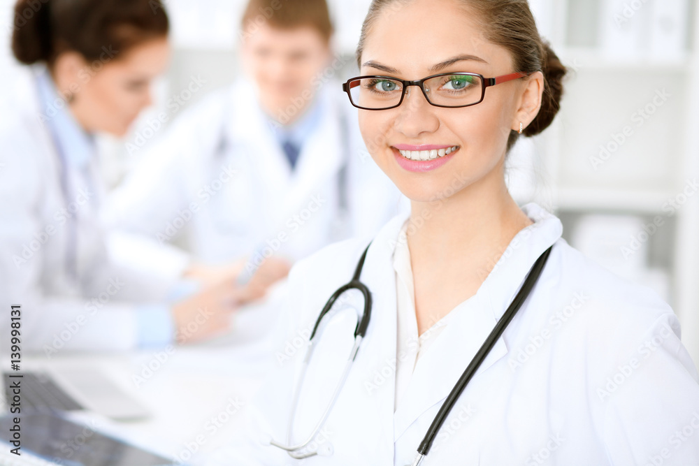 Happy doctor woman with medical staff at the hospital sitting at the table and discussing medical history Happy doctor woman with medical staff at the hospital sitting at the table and discussing medical history
