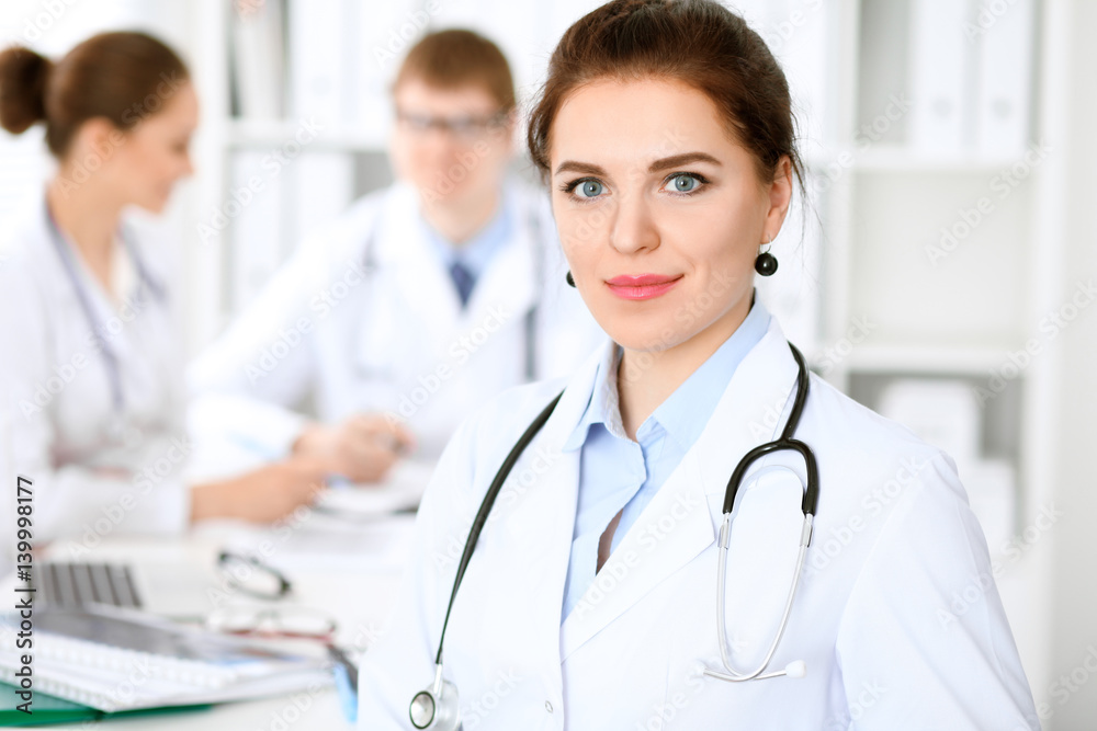 Happy doctor woman with medical staff at the hospital sitting at the table and discussing medical history Happy doctor woman with medical staff at the hospital sitting at the table and discussing medical history