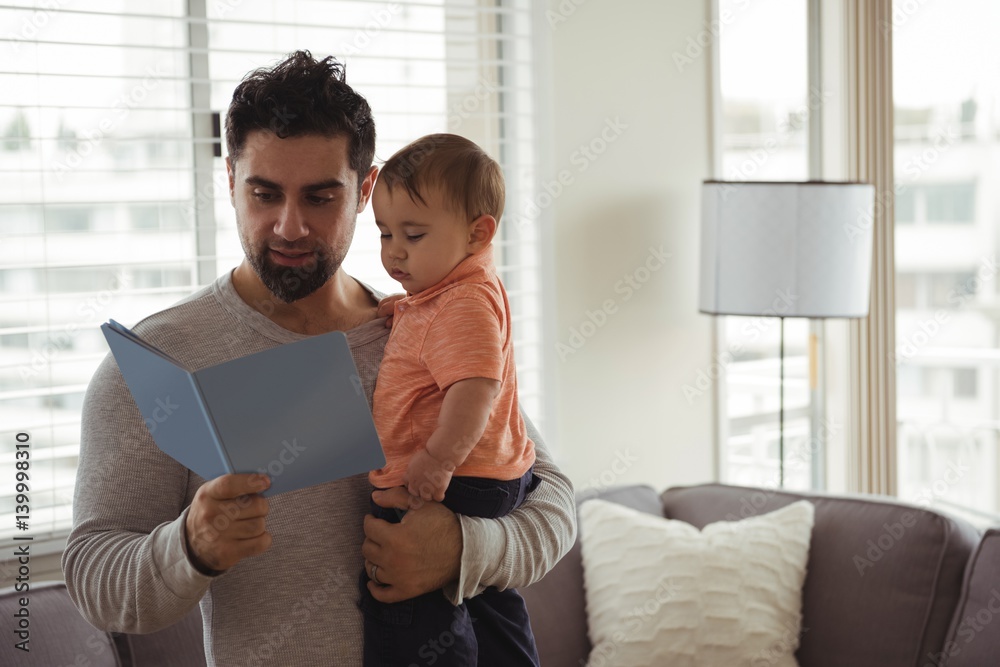 Father reading a book while holding his baby Father reading a book while holding his baby