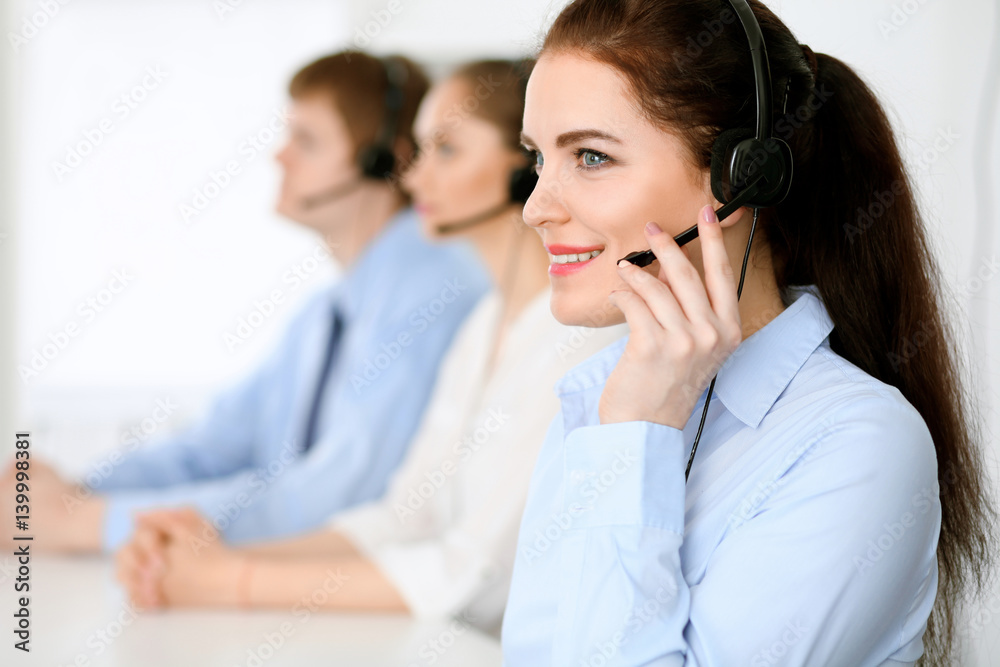 Call center operators. Focus at brunette business woman in headset Call center operators. Focus at brunette business woman in headset