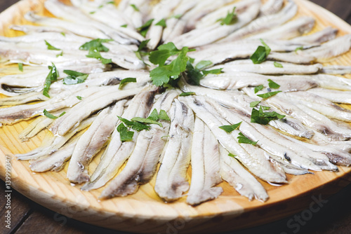 Close-up of anchovies with olive oil and vinegar on wooden plate. Healthy food.
