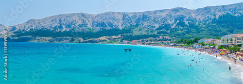 Wonderful romantic summer afternoon seascape Adriatic island. Big Beach in harbor at cristal clear blue water. Unrecognizable person - blurred faces. Baska on the island of Krk. Croatia. Europe.