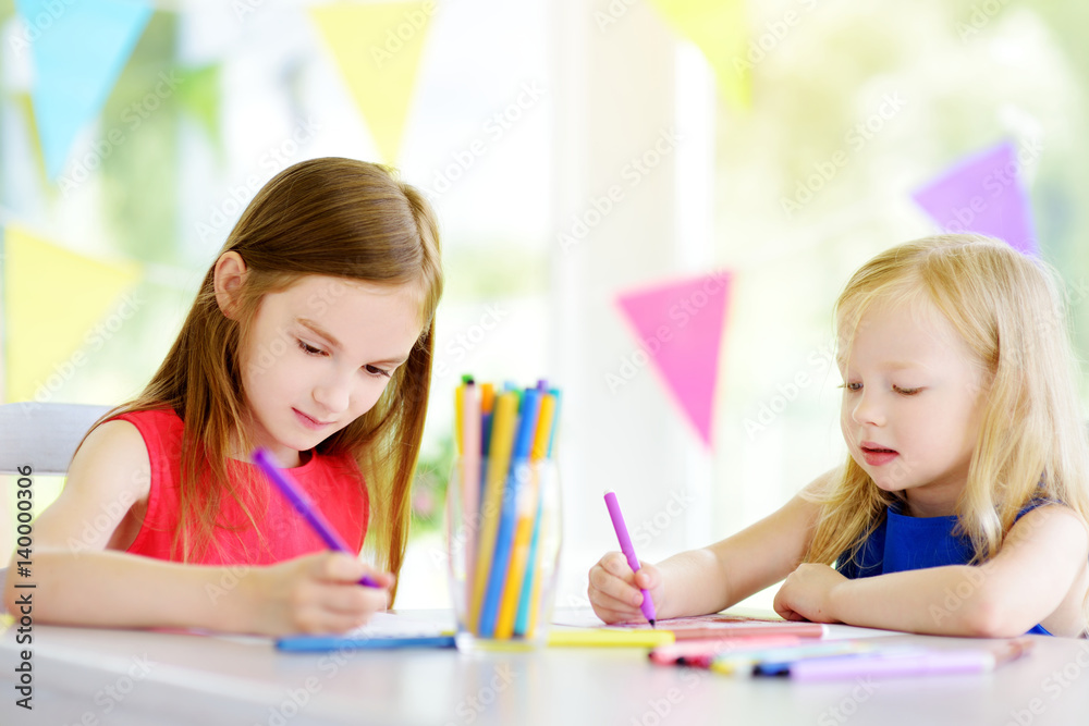 Two cute little sisters drawing with colorful pencils at a daycare. Creative kids painting together. Two cute little sisters drawing with colorful pencils at a daycare. Creative kids painting together.