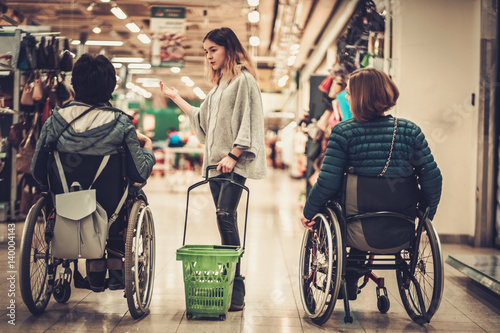 Young girl helping two disabled women in wheelchair in a department store