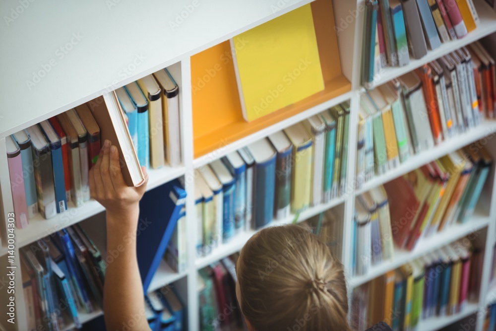 High angle view of schoolgirl selecting book High angle view of schoolgirl selecting book