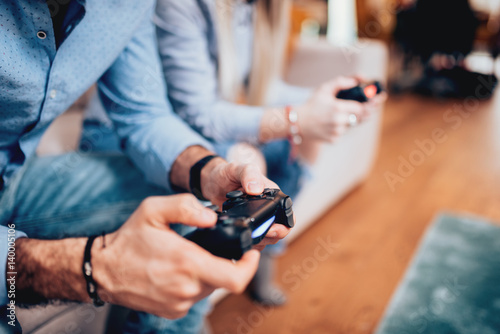 close up details of couple playing video games and using joystick controllers. Digital technology lifestyle concept