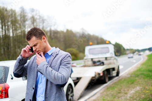 Man calling while tow truck picking up his broken car © Nejron Photo