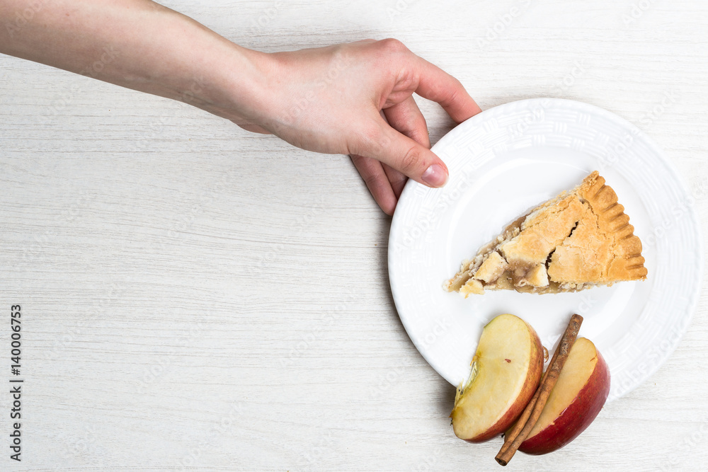 Apple pie cake lying on wooden white background in hand