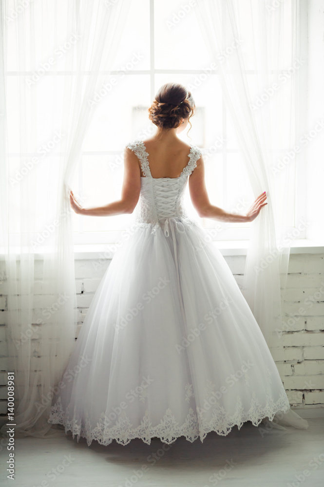 Beautiful bride with bouquet before wedding ceremony near window Beautiful bride with bouquet before wedding ceremony near window