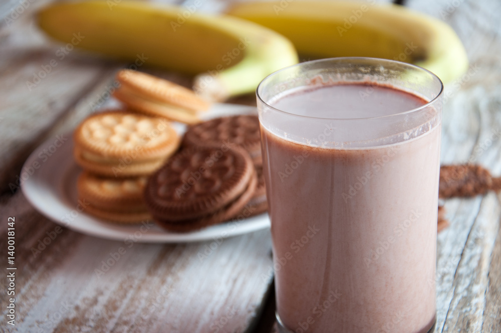 Photo of fresh Made Chocolate Banana Smoothie on a wooden table with cookies. Photo of fresh Made Chocolate Banana Smoothie on a wooden table with cookies.