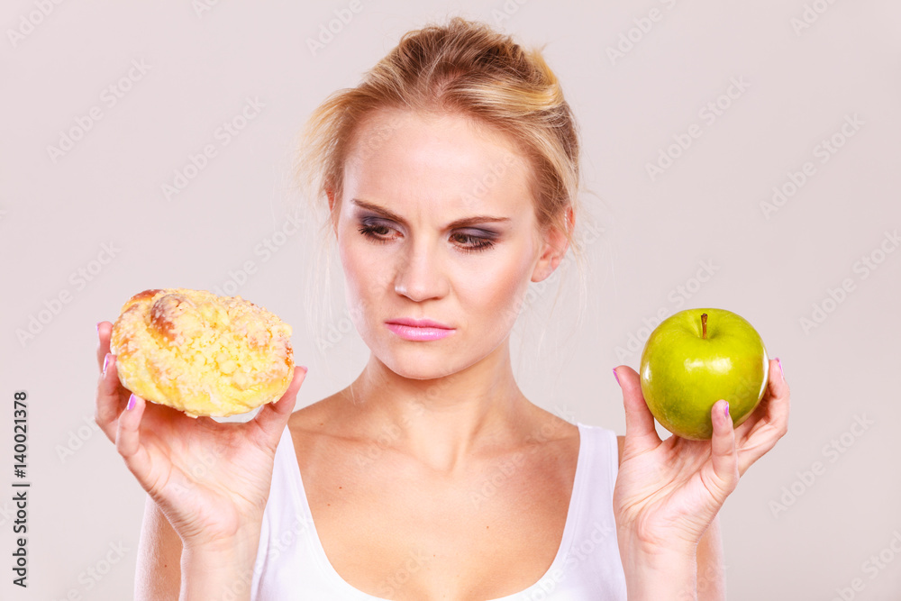 Woman holds cake and fruit in hand choosing Woman holds cake and fruit in hand choosing