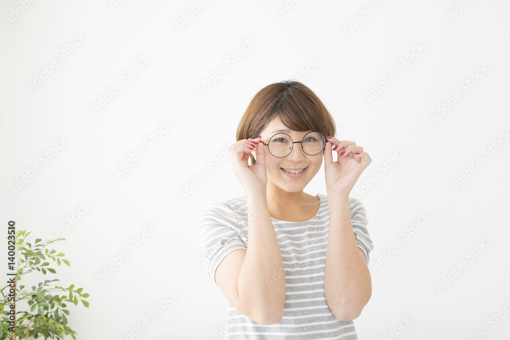 眼鏡の若い女性　ポートレート　笑顔でカメラ目線　室内　白バック