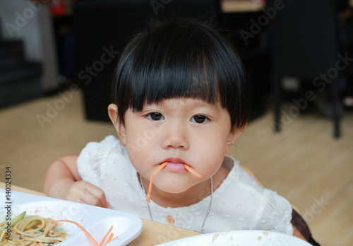 Funny kid girl eating carrot.  