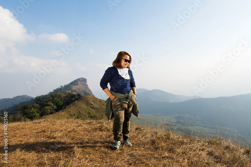 happy woman smile and stand on top mountain at morning light, subject is soft focus © suparat1983