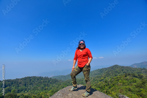 happy woman smile and stand on top mountain with blue sky at sunny day, subject is soft focus