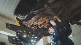 Under bottom of car - Worker mechanic checks - automobile service