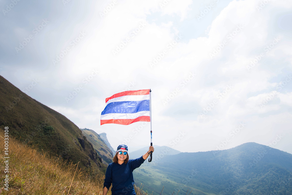 Obraz premium happy woman smile and holding Thai flag on mountain at sunny day. subject is blurred