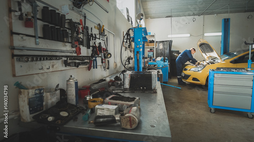 Mechanic in the garage, car preparing for repairing, wide angle