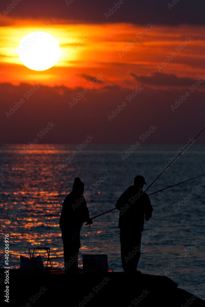 Fishermen at the seashore at sunset