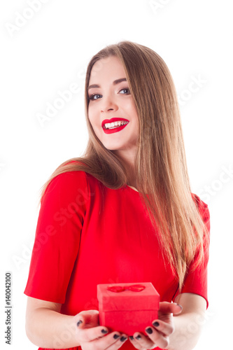 Young stylish and beautiful model girl with a smile, red lipstick in a red dress and with a gift, isolate on a white background