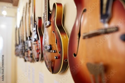 Old excellent electro and bass guitars on the shelf in the guitar shop