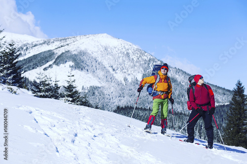 Winter hiking in the mountains on snowshoes with a backpack and tent. © vetal1983