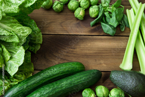 Products containing folic acid - B9 vitamin . Green vegetables on wooden background. Celery, avocado, Brussels sprouts, basil, cucumber, romaine salad