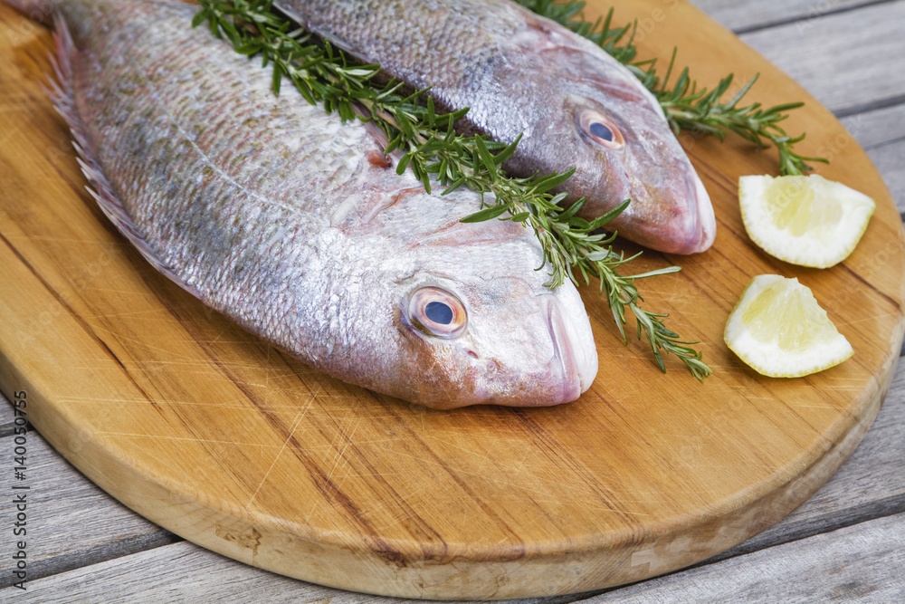 Red snapper with rosemary and lemon on chopping board Red snapper with rosemary and lemon on chopping board