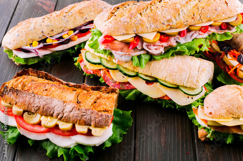 Different kinds of delicious wholemeal sandwiches lie on dark wooden table