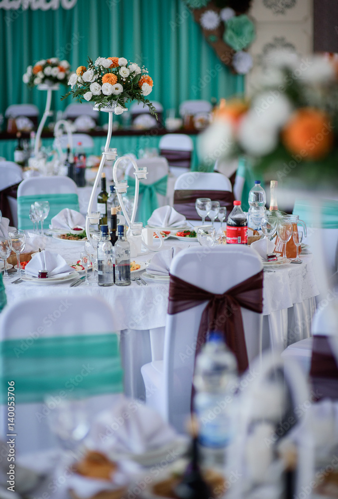 Fototapeta premium Chairs twined with brown cloth stand around dinner tables ready for wedding party