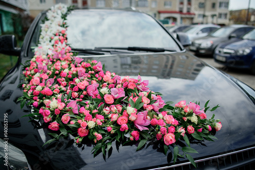 Pink roses and tulips lie on black car hood