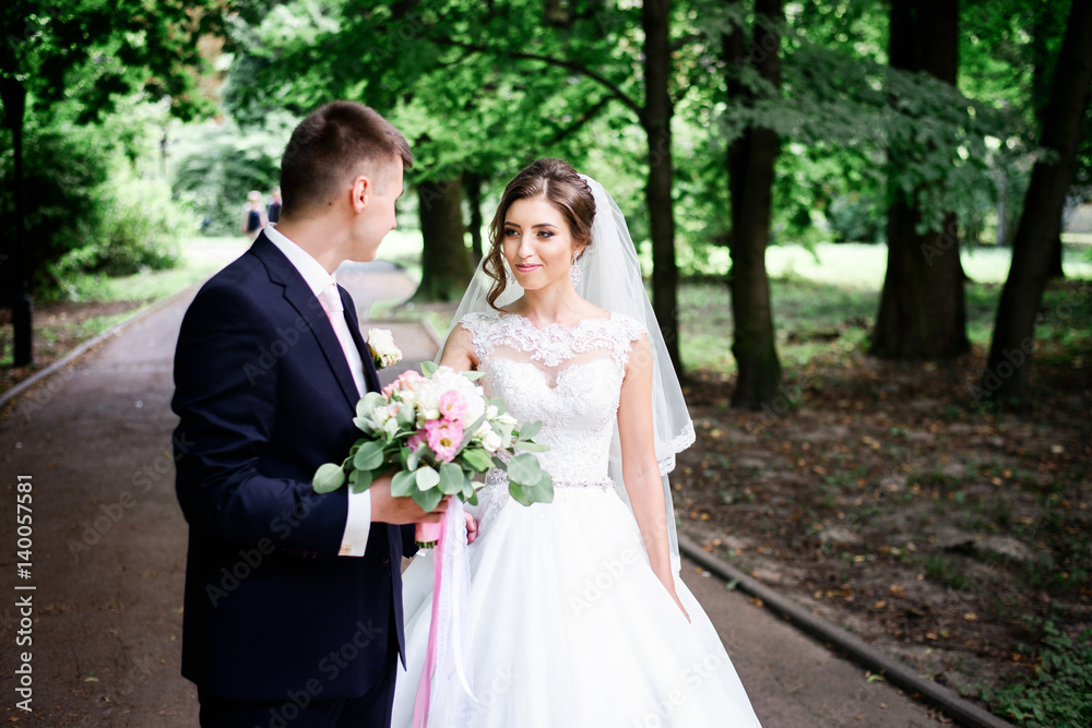 Happy newlyweds walk along the path in park Happy newlyweds walk along the path in park