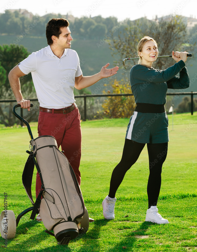 Fototapeta premium Man 30-35 years old is showing woman 25-29 years old to play golf