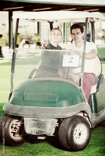 Male and female golf partners using golf cart
