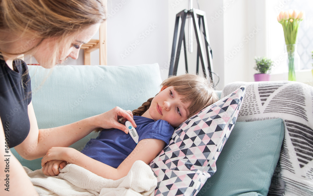 Fototapeta premium Sick little girl lying in bed mother checking her temperature
